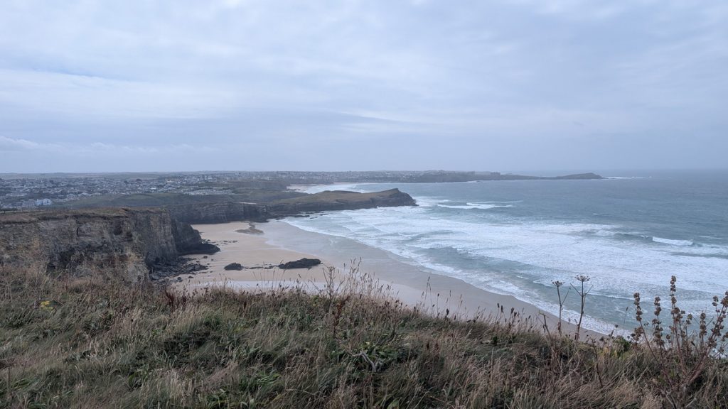 Looking across Whipsiderry Beach to Porth Island with Newquay in the distance